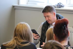 Youth worker checking his phone in front of a group of young people