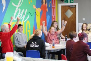 Group of young people sitting at a table in a youth club having fun