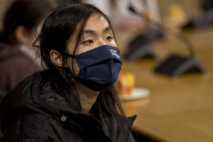Young woman sits in scottish parliament with a facemask on during Covid