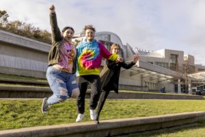 Three young people jumping in the air outside of the Scottish Parliament. Picture: Alan Rennie