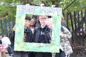 Group of young people in front of a large frame with 'Eco Fest'written along the top
