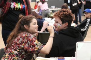 Young person having their face painted at an eco event
