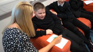 A young boy gets help filling out a form by a youth worker.