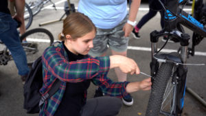 A young person tightens a screw on a bike.