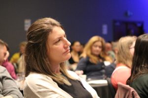 Woman listening intently to a presentation at a conference.