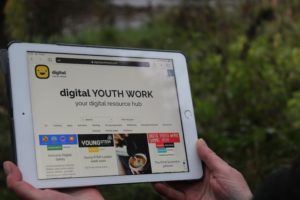 Person holding iPad with the Digital Youth Work dot Scot website