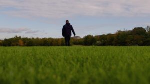 Young person walking away in field