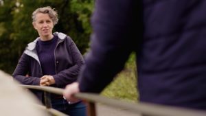 Youth worker talking to young person on a bridge over a cycling path