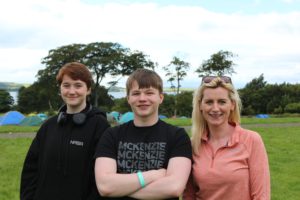 A youth worker stands beside two young people, smiling for a photo