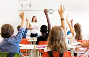 children with raised hands in classroom