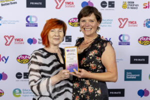 Equality & Diversity awards winners press shot at the national youth work awards. Two women hold the trophy, smiling.