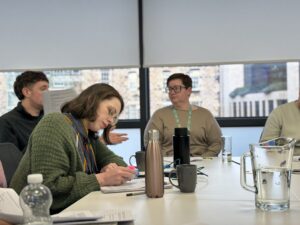 Two women and a man sat at a table discussing research