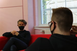 A female youth worker and young person talking wearing masks