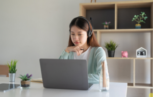 Young woman sitting in front of a laptop with headphones on