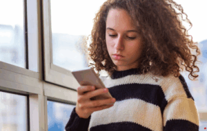Girl holding a mobile phone looking lonely.