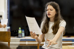 A young person reads from a script in a drama class.