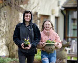 Picture of two young people carrying flowers in planters