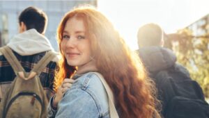 Girl looks back at camera smiling whilst walking with a a group of friends