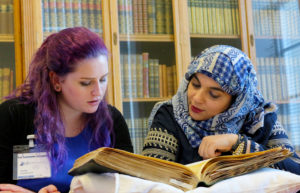 2 female youth workers reading a book in the National Library of Scotland
