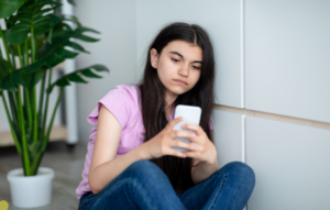Girl sitting with a mobile phone looking sad