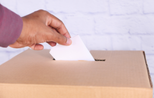 A hand posting a vote in a box