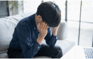 Young man sitting holding his head