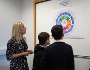 Youth worker and two young boys examine the youth work outcomes and skills framework on a whiteboard